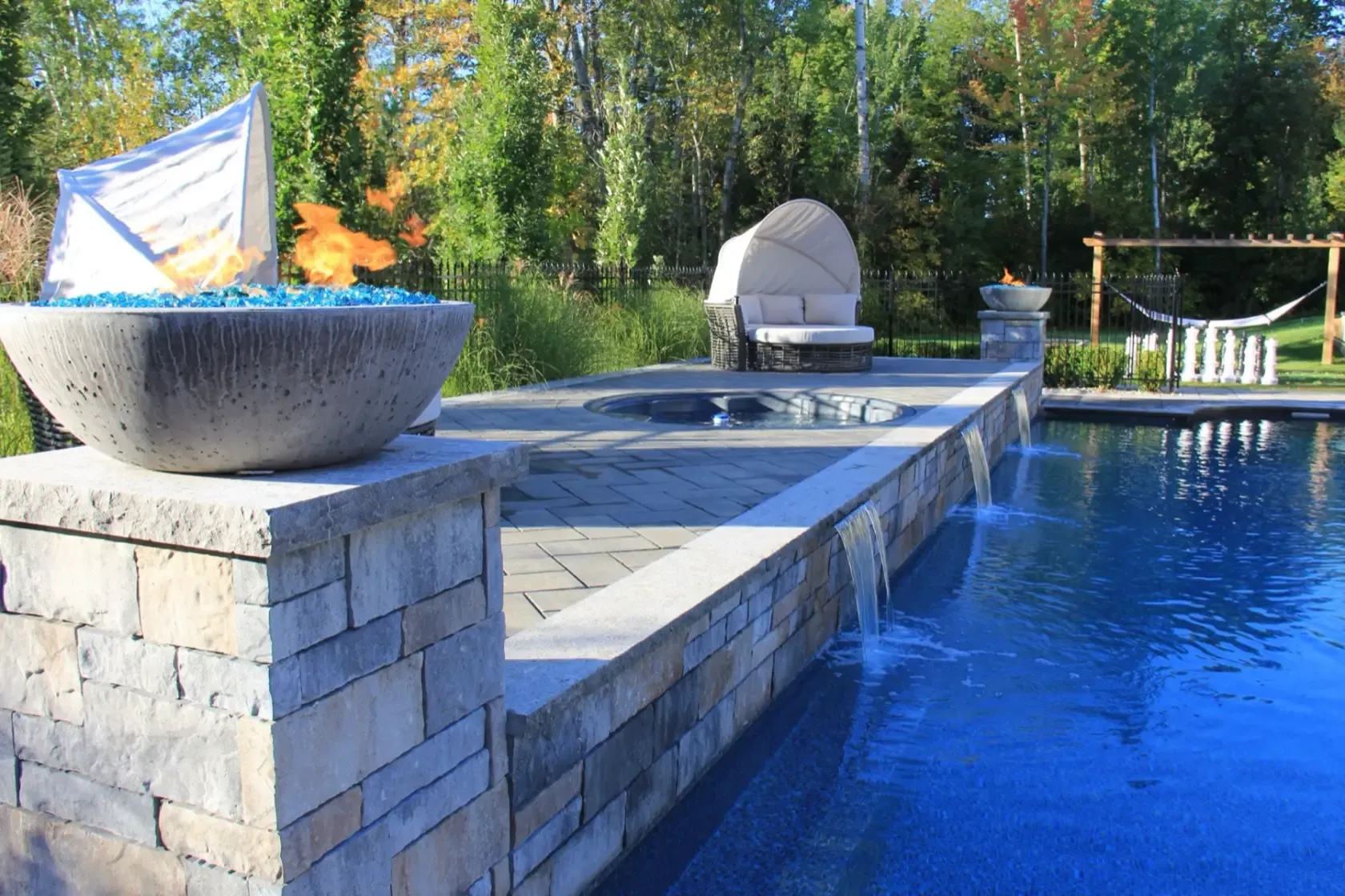 Blue-glass fire bowl beside a waterfall spillway in golden light