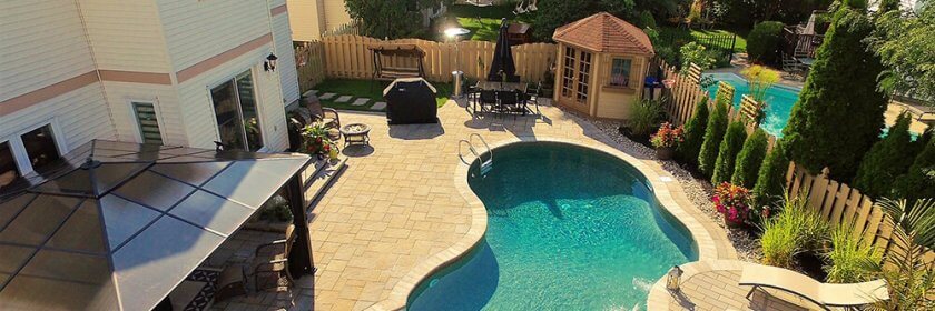 An aerial shot of a compact backyard pool and patio.